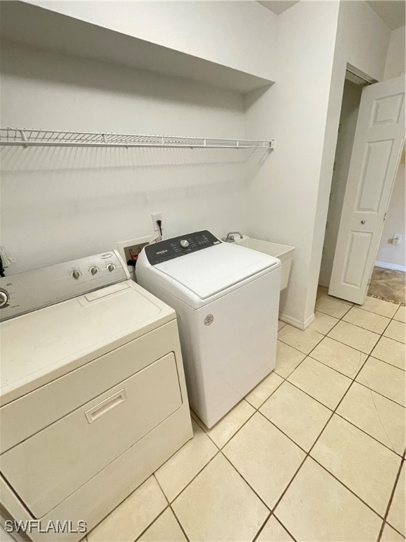 clothes washing area with light tile patterned floors, sink, and independent washer and dryer