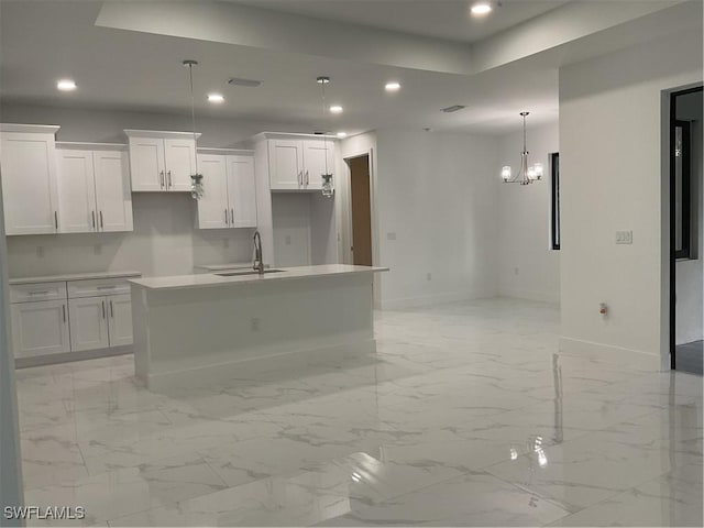 kitchen with a center island with sink, white cabinetry, sink, and hanging light fixtures