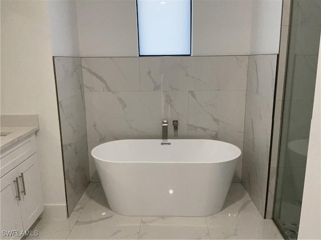 bathroom with vanity, a bath, and tile walls