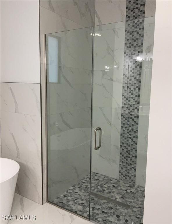 bathroom with tile walls and shower with separate bathtub