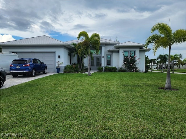 view of front facade with french doors, stucco siding, a front yard, a garage, and driveway