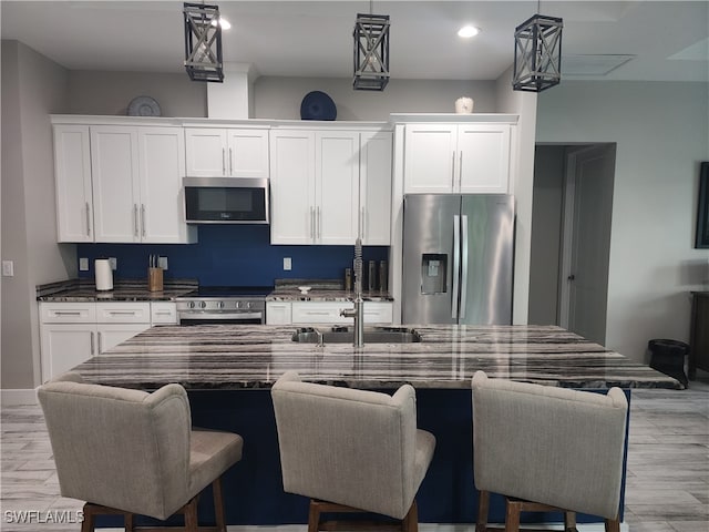 kitchen with appliances with stainless steel finishes, a kitchen breakfast bar, and light hardwood / wood-style floors