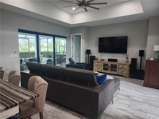 living room with a tray ceiling, wood-type flooring, and ceiling fan