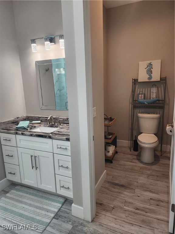 bathroom with hardwood / wood-style floors, toilet, and vanity