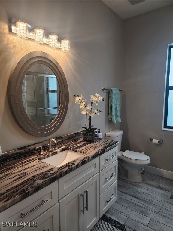 bathroom with vanity, toilet, hardwood / wood-style floors, and an enclosed shower