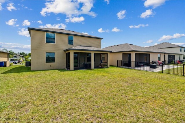 back of house featuring a lawn, a patio, and a sunroom