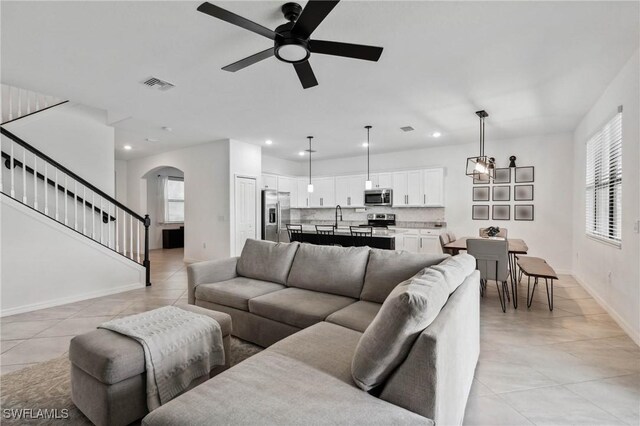 tiled living room with sink and ceiling fan with notable chandelier