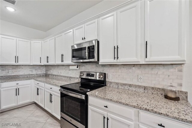 kitchen with appliances with stainless steel finishes, light tile patterned floors, and white cabinetry