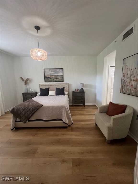 bedroom with hardwood / wood-style flooring and a chandelier