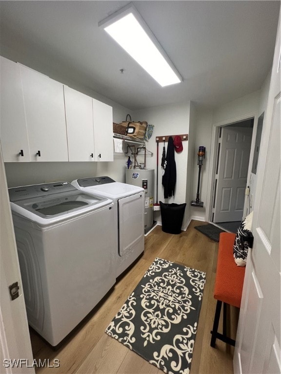 laundry room with cabinets, washer and clothes dryer, electric water heater, and light wood-type flooring