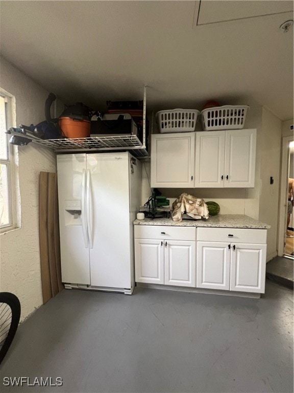 interior space with white cabinetry, concrete floors, and white fridge with ice dispenser