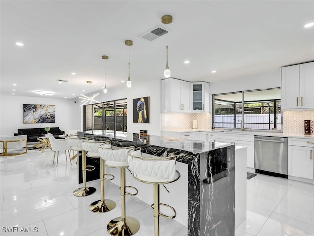 kitchen featuring dishwasher, a healthy amount of sunlight, a kitchen breakfast bar, and white cabinetry