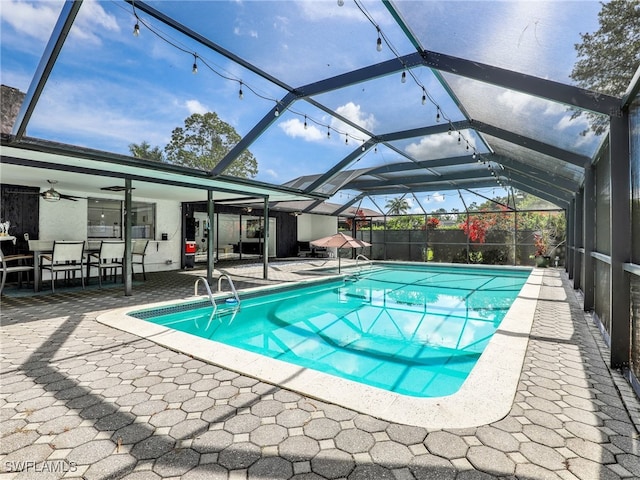 view of pool with a patio, glass enclosure, and ceiling fan