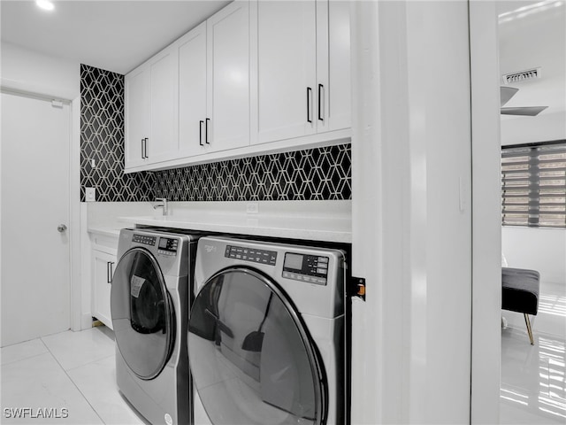 washroom featuring washer and clothes dryer, cabinets, and light tile patterned floors