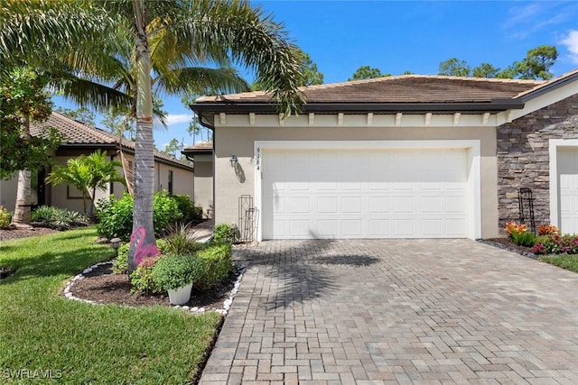 ranch-style home with stone siding, stucco siding, an attached garage, and decorative driveway