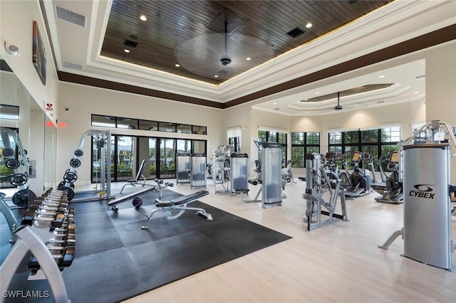 workout area featuring visible vents, a raised ceiling, and ornamental molding