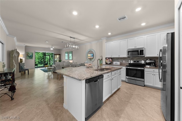 kitchen featuring visible vents, a sink, open floor plan, stainless steel appliances, and crown molding