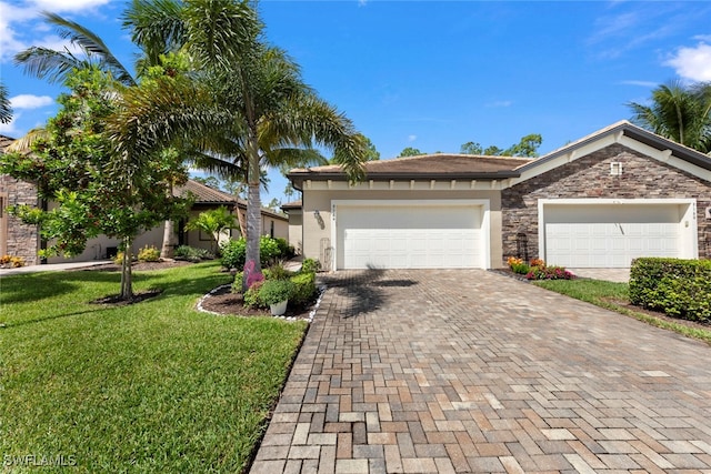 view of front facade featuring stucco siding, decorative driveway, stone siding, a front yard, and a garage