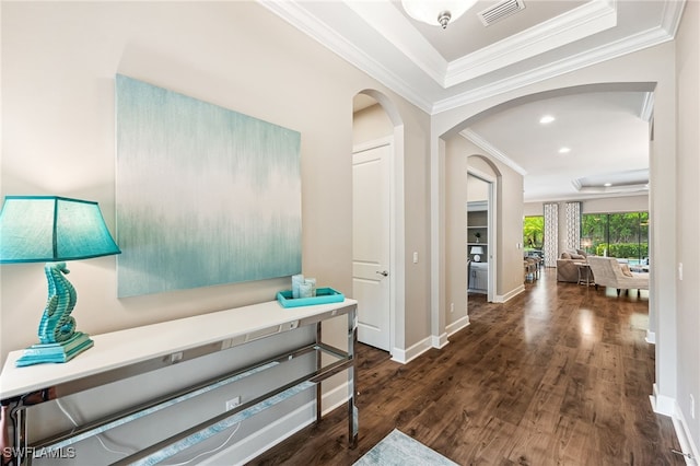 hallway with visible vents, crown molding, baseboards, wood finished floors, and arched walkways