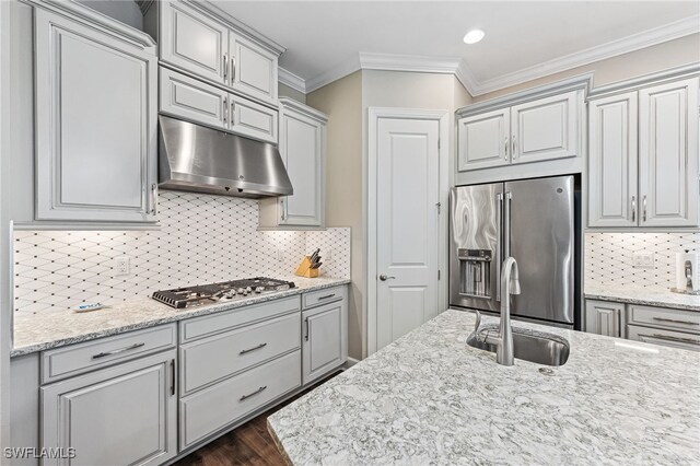 kitchen with under cabinet range hood, dark wood-style flooring, a sink, appliances with stainless steel finishes, and crown molding