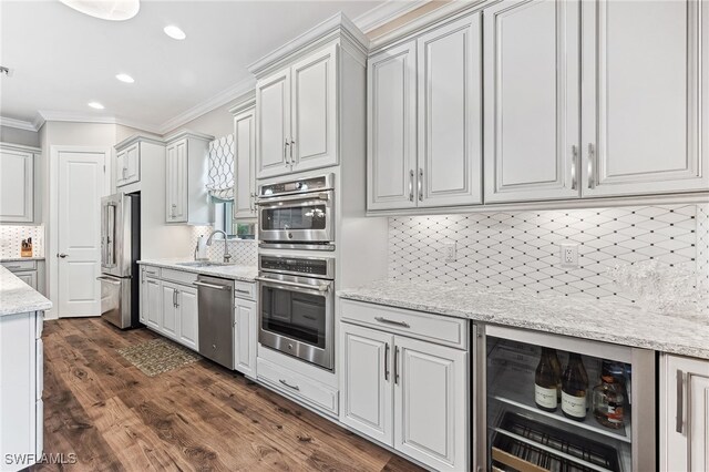 kitchen with crown molding, appliances with stainless steel finishes, a sink, and white cabinets