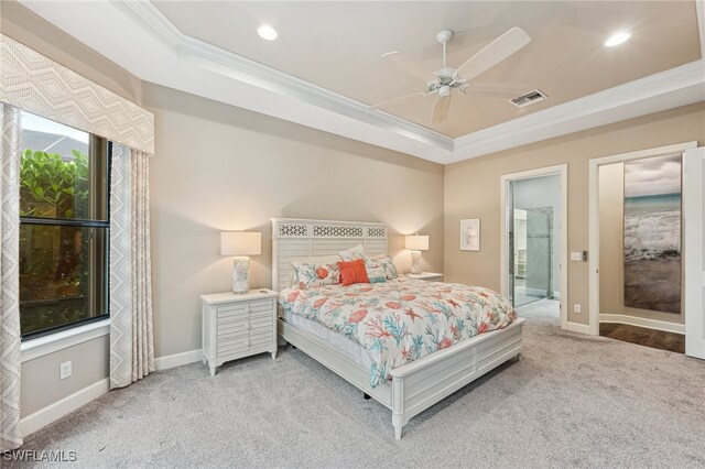 bedroom featuring light colored carpet, visible vents, baseboards, a tray ceiling, and crown molding