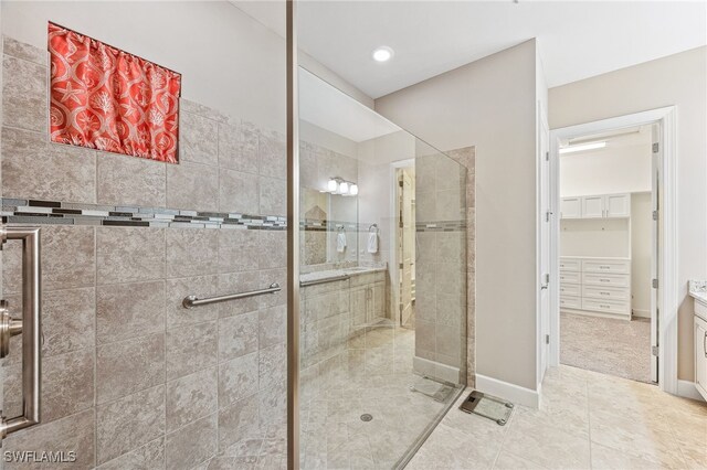 full bathroom featuring vanity, baseboards, a spacious closet, tile patterned floors, and a stall shower