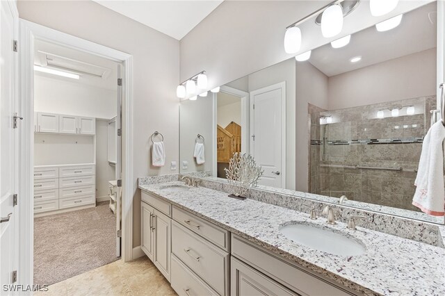 full bathroom featuring double vanity, a spacious closet, walk in shower, and a sink