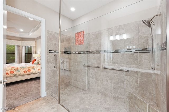 ensuite bathroom with recessed lighting, a tray ceiling, ensuite bathroom, and a tile shower