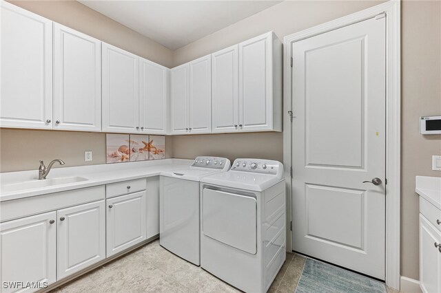 laundry area featuring washing machine and clothes dryer, a sink, and cabinet space