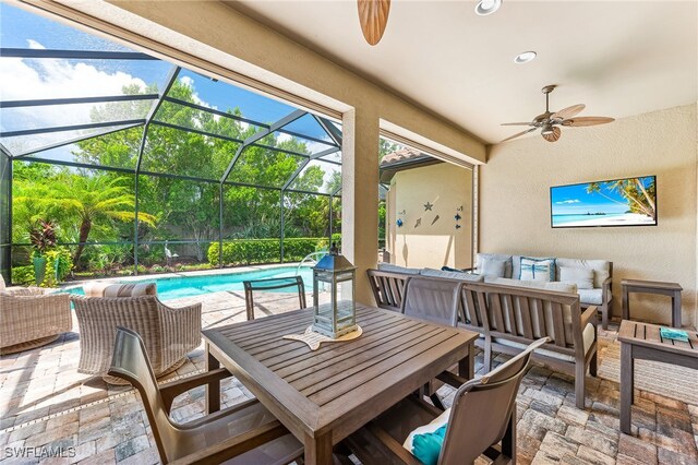 view of patio / terrace featuring an outdoor pool, glass enclosure, outdoor lounge area, and ceiling fan