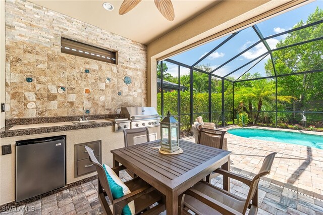 view of patio featuring an outdoor pool, ceiling fan, a lanai, a grill, and exterior kitchen