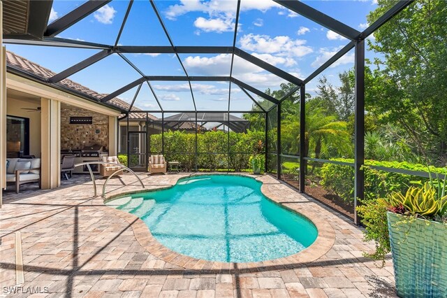 pool featuring ceiling fan, glass enclosure, and a patio area