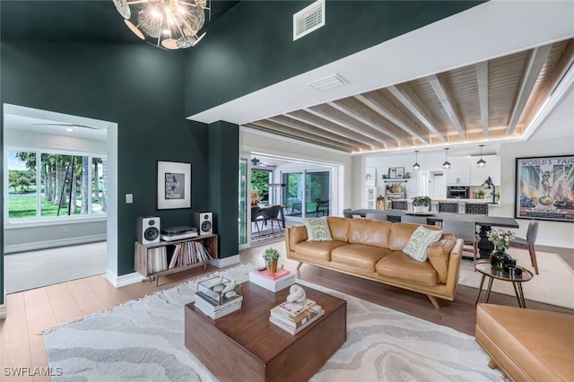 living room featuring hardwood / wood-style floors, beamed ceiling, and an inviting chandelier