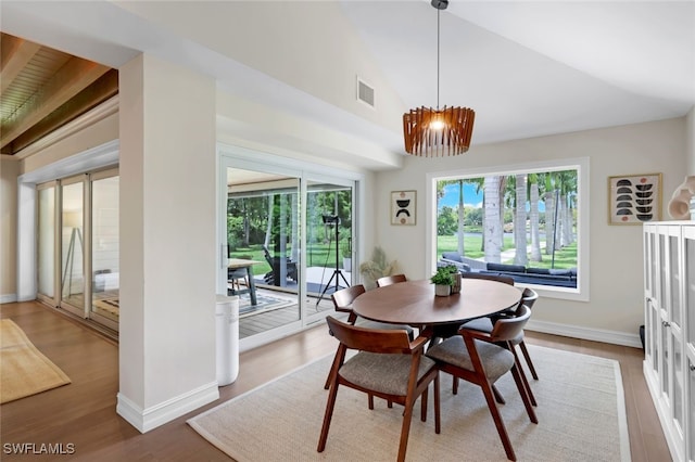 dining space featuring lofted ceiling, hardwood / wood-style flooring, and an inviting chandelier