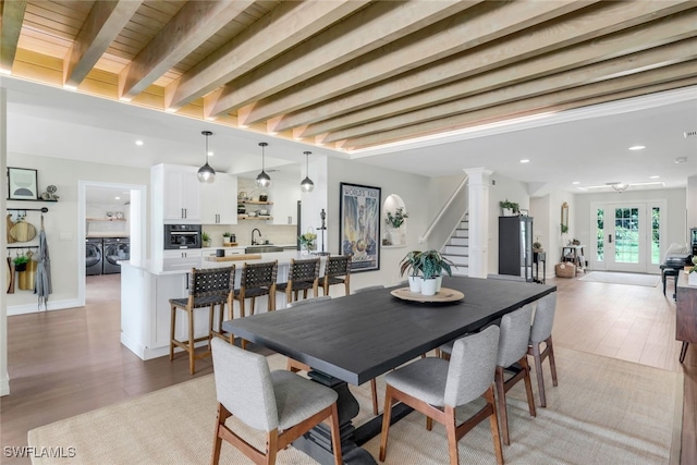 dining room with light hardwood / wood-style floors, beamed ceiling, sink, and independent washer and dryer