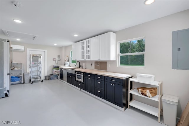 kitchen with white cabinetry, a wall unit AC, sink, and electric panel