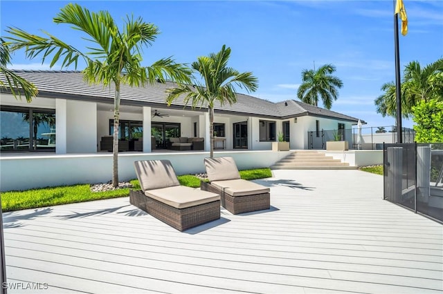 wooden terrace featuring fence, an outdoor living space, and a ceiling fan