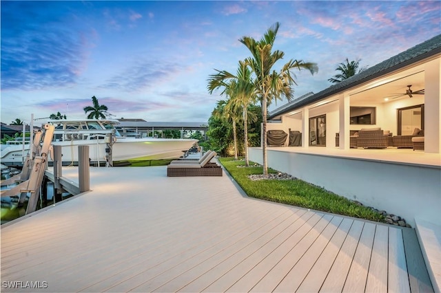 deck at dusk featuring a boat dock, boat lift, and outdoor lounge area