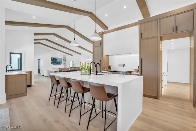 kitchen featuring a kitchen breakfast bar, a large island, beamed ceiling, and light wood-style floors