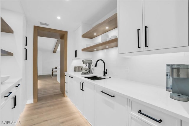 kitchen featuring white cabinetry, open shelves, a sink, and light countertops