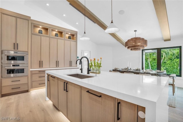 kitchen with light wood-style flooring, vaulted ceiling with beams, light countertops, light brown cabinetry, and a sink