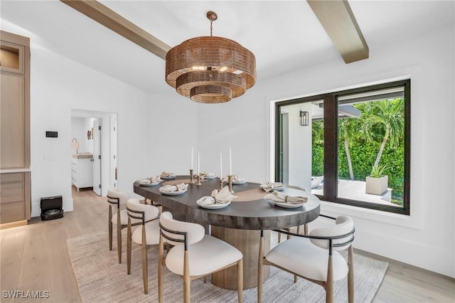 dining space with a chandelier, light wood-type flooring, and vaulted ceiling with beams