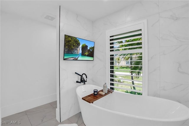 full bathroom with a freestanding bath, marble finish floor, and tile walls