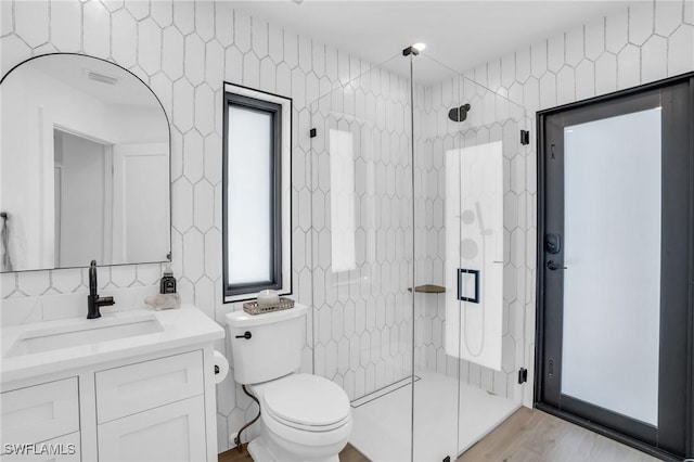 bathroom with toilet, visible vents, vanity, tile walls, and a shower stall