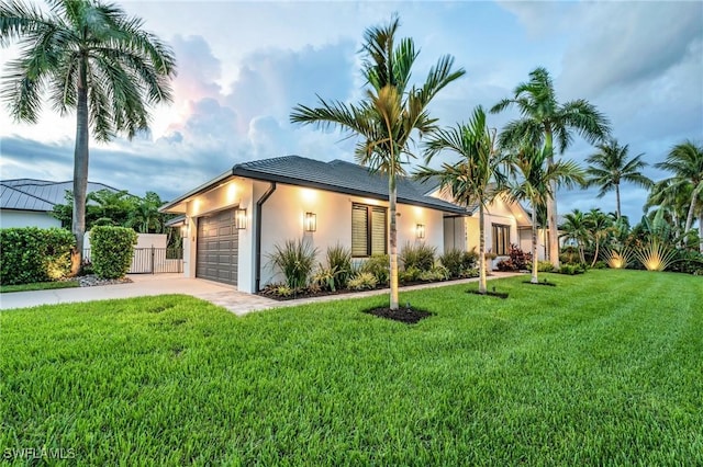 view of front of property with stucco siding, an attached garage, a front yard, fence, and driveway