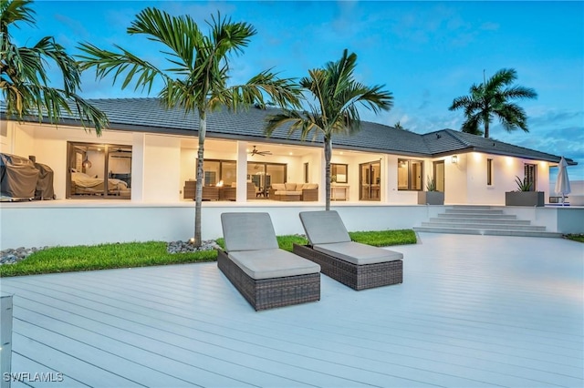 rear view of house featuring outdoor lounge area, a wooden deck, a ceiling fan, and stucco siding