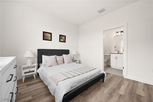 bedroom featuring light wood-type flooring and ensuite bath