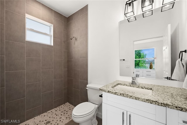 bathroom featuring vanity, toilet, and a tile shower