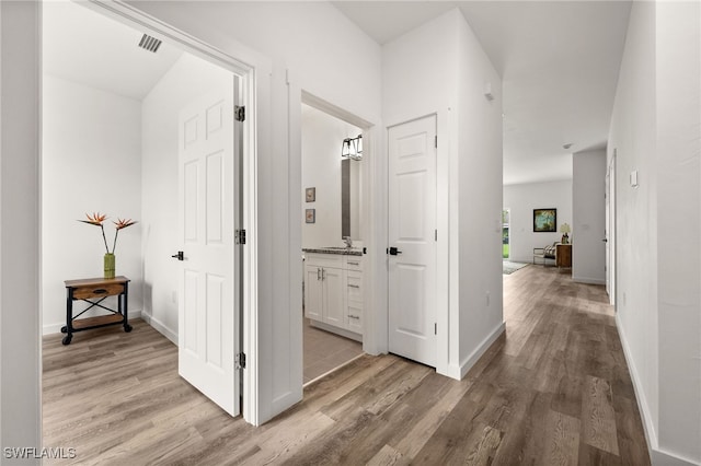 corridor featuring sink and light hardwood / wood-style floors